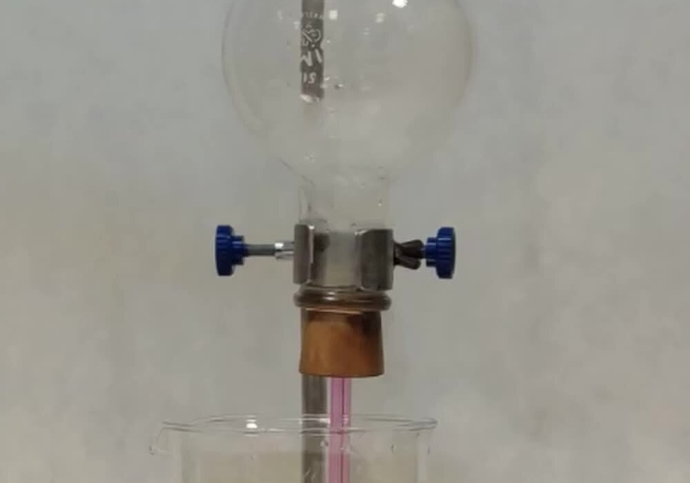 A flask and beaker in which a clear liquid turns pink as it rises