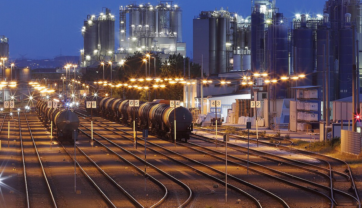 A chemical works at dusk, tank wagons standing on a yard of lit railway sidings